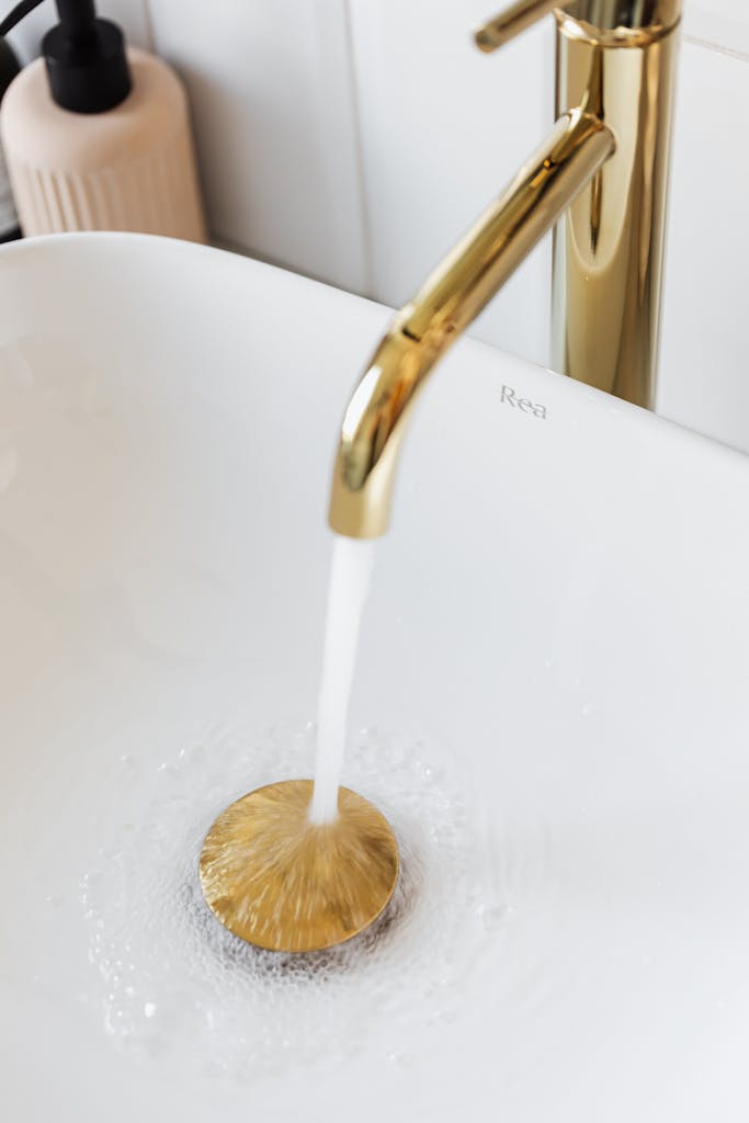 Luxurious gold bathroom faucet with running water in a modern sink, perfect for upscale interiors.